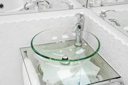 Glass washbasin on glass table and corner mirror in bathroom
